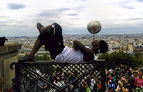 Picture of man balancing soccer ball on a pencil in his mouth